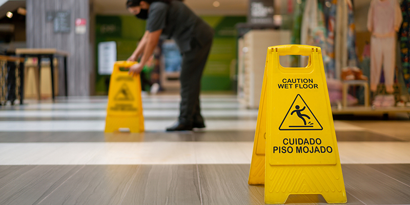 employee putting caution signs on wet floor